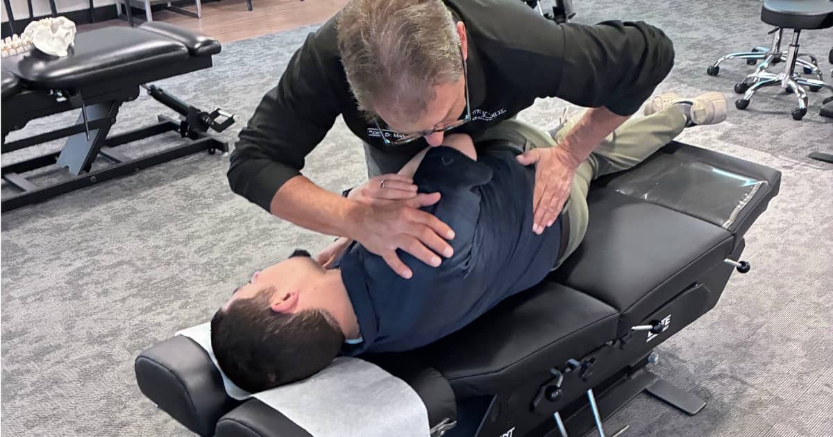 Chiropractor providing a side-posture adjustment to a patient at The Joint Chiropractic in West Alli