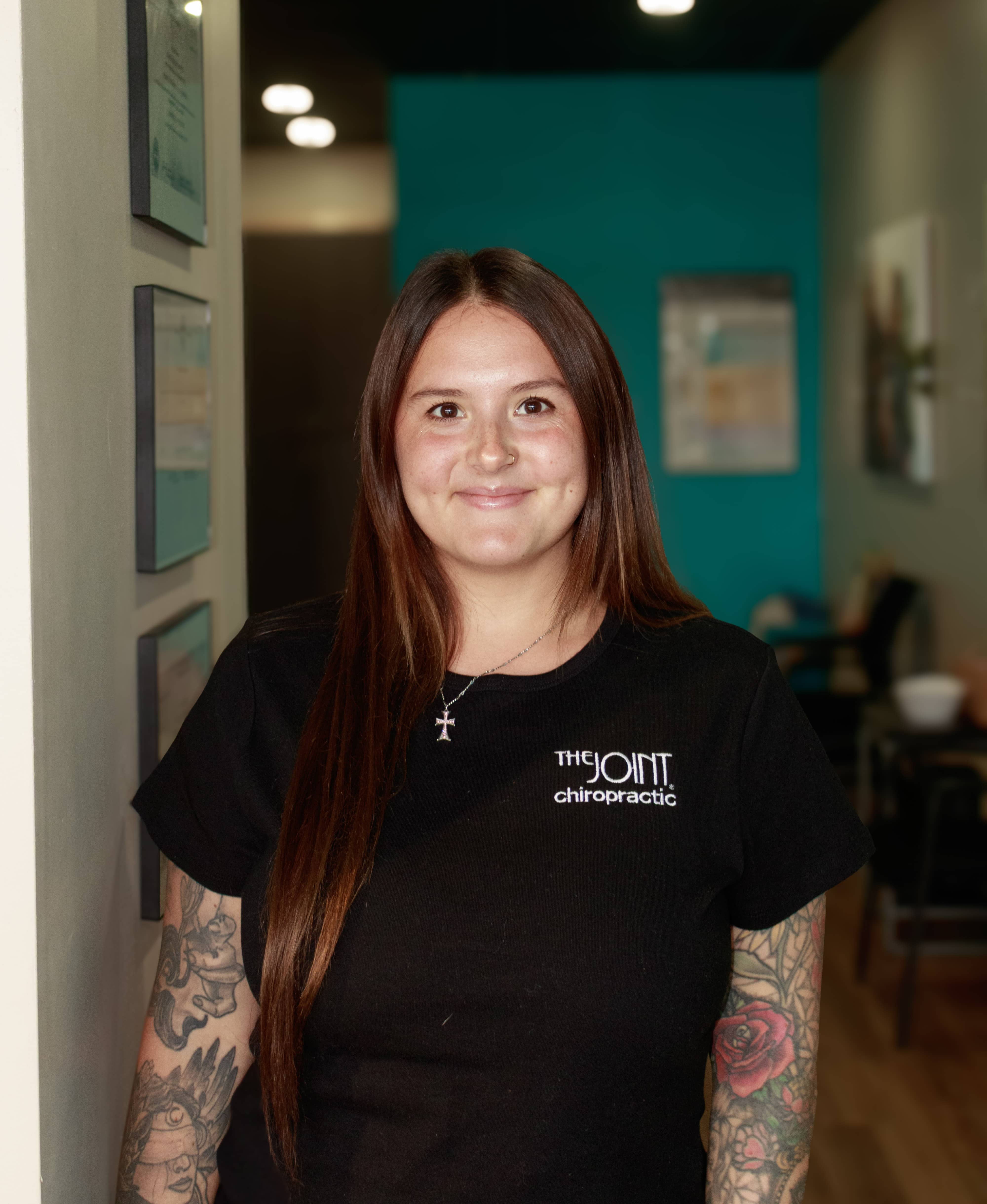 This image shows a Wellness Coordinator team member wearing a black The Joint Chiropractic branded t